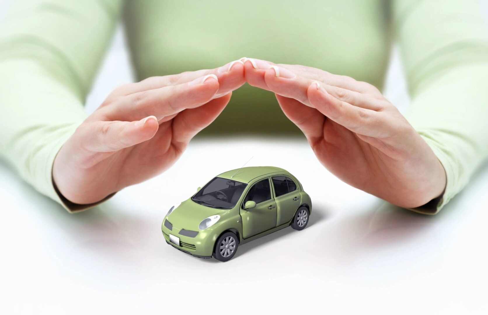 Small green car under a pair of hands